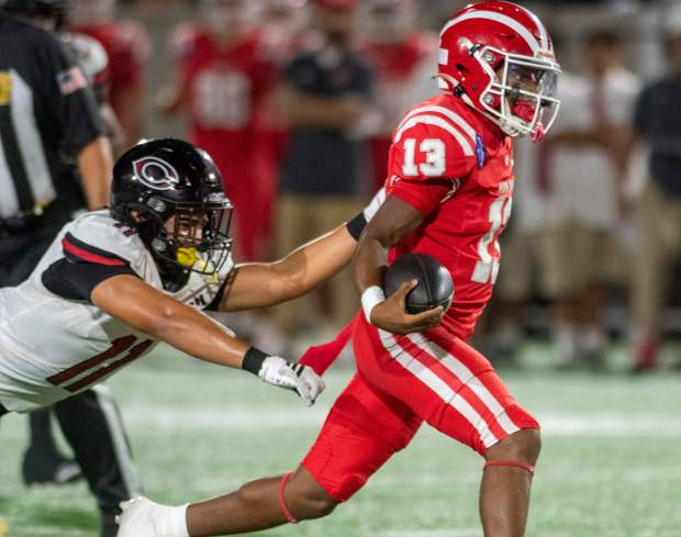 Mater Dei's Paytyn Guess (13) escapes the grasp of Centennial's Chase Wallner (11) during a high school football game between Centennial of Corona and Mater Dei in a non-league contest at Santa Ana Stadium.September 11, 2026.(Photo by Michael Goulding, Contributing Photographer)