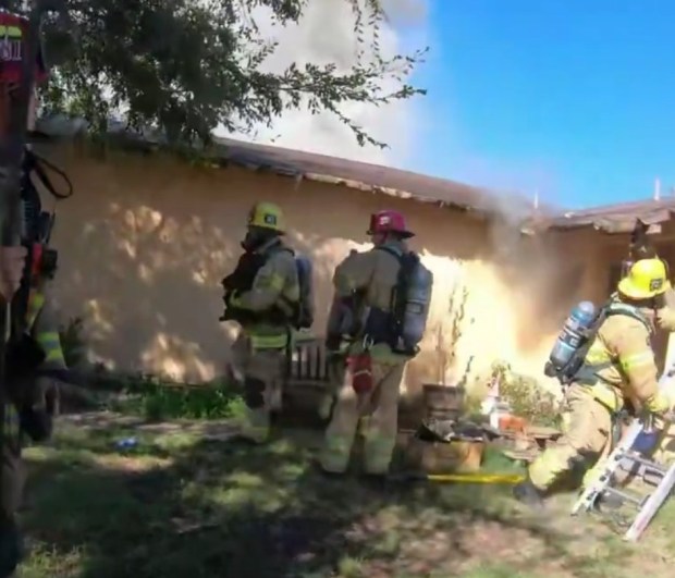The firefighter on the left, wearing a yellow helmet, is seen carrying Agusta the dog to safety on Monday, Aug. 31, 2026, from a burning home in Santa Ana. (Photo courtesy of the Santa Ana Fire Authority)