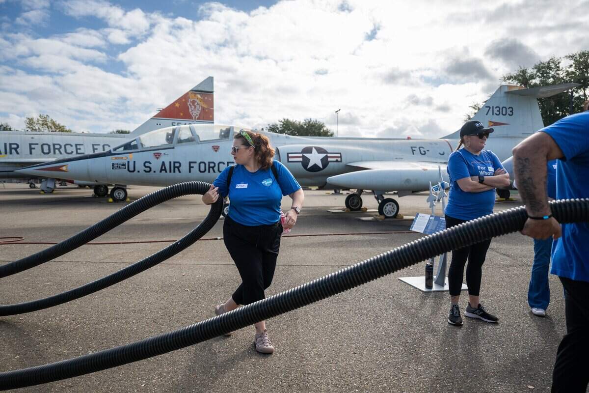 A volunteer helps carry a fire hose to wash aircraft exhibits at the Aerospace Museum of California in Sacramento on Thursday.