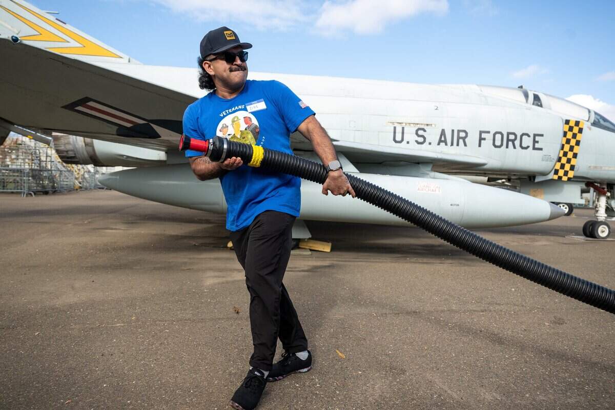 Dre Hernandez carries fire hose to wash airplanes at the Aerospace Museum of California in Sacramento on Thursday.