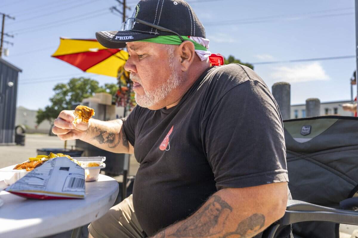Paul Martinez of Sacramento enjoys a chili dog from Between the Buns 916, a hot dog stand owned by former state worker Drew Schmidt, on Thursday, Sept. 10, 2026.