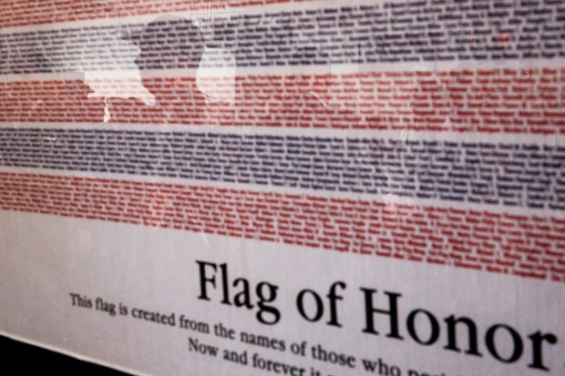 Attendees are reflected in a framed Flag of Honor, which was created with the names of those who died in the Sept. 11 attacks in 2001, during the Patriot Day ceremony on the 25th anniversary of the Sept. 11 attacks in downtown San Jose on Friday, Sept. 11, 2026. (Dai Sugano/Bay Area News Group)