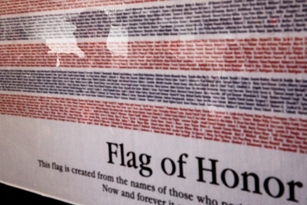 Attendees are reflected in a framed Flag of Honor, which was created with the names of those who died in the Sept. 11 attacks in 2001, during the Patriot Day ceremony on the 25th anniversary of the Sept. 11 attacks in downtown San Jose on Friday, Sept. 11, 2026. (Dai Sugano/Bay Area News Group)