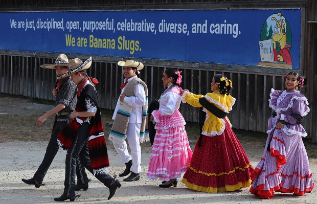 Dancers walk past the welcome sign at the base of campus as they head to another location for a photo. (Shmuel Thaler Santa Cruz Sentinel)