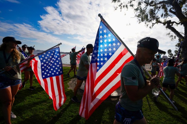 CORONADO, CA - SEPTEMBER 19, 2026: Participants in the 6th annual Swim for SOF ( Special Operations Forces), put on by the Honor Foundation, finish the flag run from the beach near the Hotel Del Coronado to Glorietta Bay Park where the 3.2 mile swim to the USS Midway Museum began, that included a stop for push-ups and pull-ups at Tidelands Park, Saturday September 19, 2026, in Coronado, California. (Howard Lipin / For The San Diego Union-Tribune)