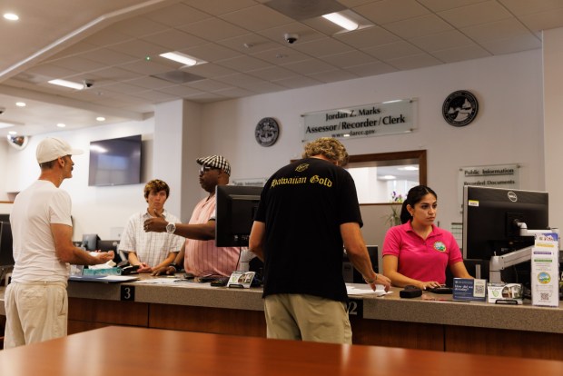 San Diego, California - Rosa Garay Benavides, senior assessment clerk, right, helps a member of the public inside the Assessor's office at the County Administration Center on Wednesday, Sept. 2, 2026. The COBOL system is displayed on the monitor beside her. (Kristian Carreon / The San Diego Union-Tribune)