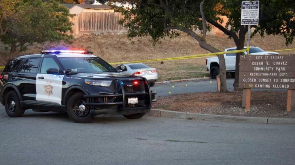 A police car with flashing lights at a crime scene blocked off with yellow tape at Cesar E Chavez Community Park.