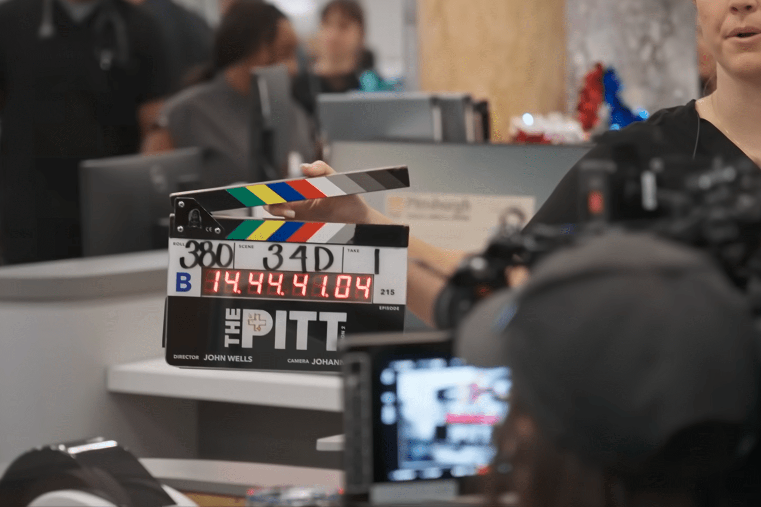 A woman holds a clapperboard in front of a camera on the set of The Pitt.