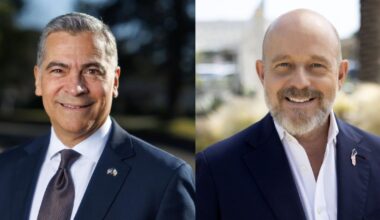 Side by side photos of two men, both wearing navy blue suit jackets with American flags on the left lapels, over white shirts. The man on the left has short gray hair and is clean-shaven and wearing a blue tie. The man on the right is bald with a trim gray beard and mustache and has his top two shirt buttons undone.