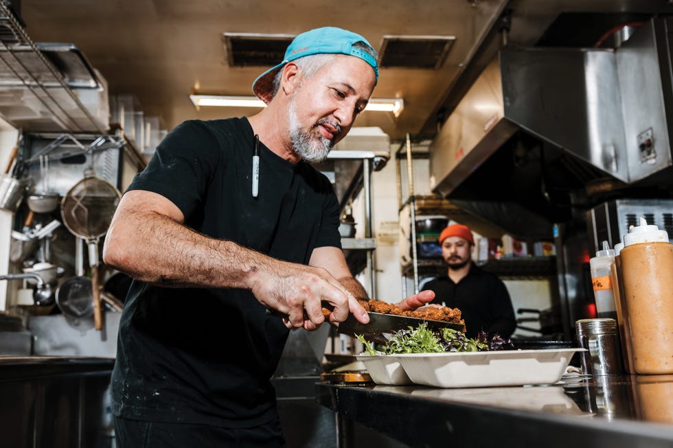chef preparing a salad in a busy kitchen environment, chef anthony rizzi in the kitchen, lou's takeaway, san rafael california, 25 restaurants defining california dining