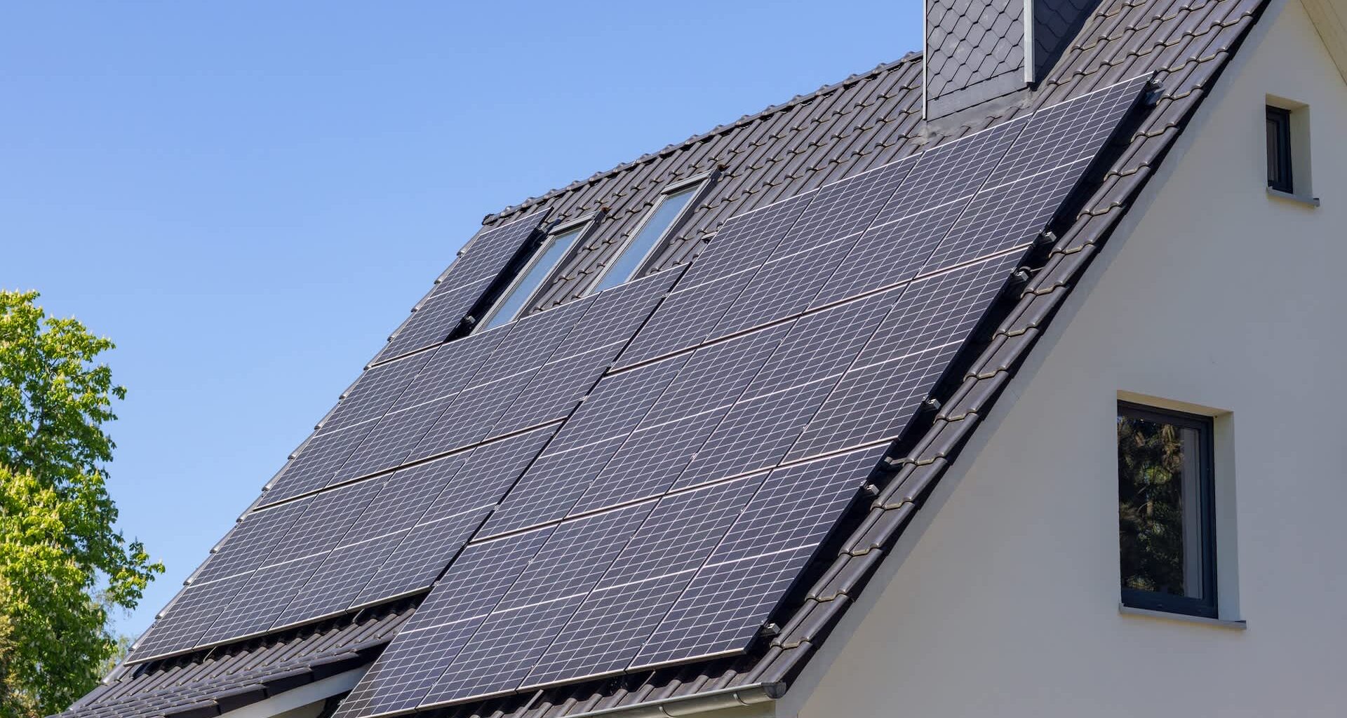 Solar panels installed on the roof of a house under a clear blue sky.