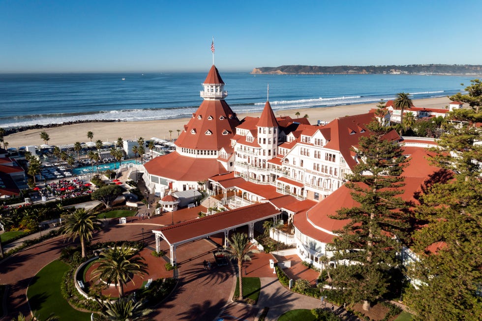 Historic beachfront hotel with red roofs, palm trees, and ocean views.