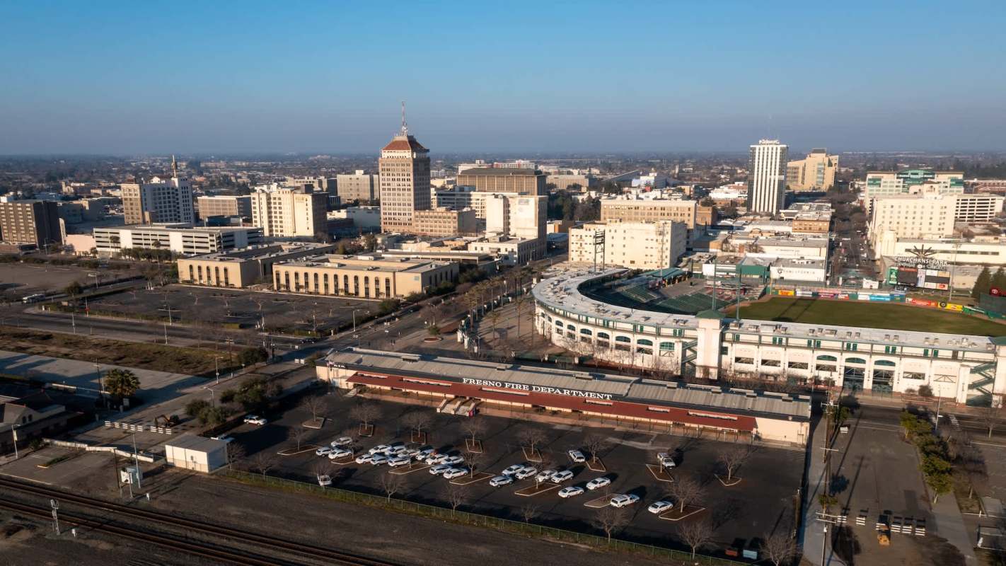 Aerial view of downtown Fresno with buildings, parking lots, and a baseball stadium.