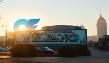 a building with a mural with sunrise and an only fans logo rising over the building