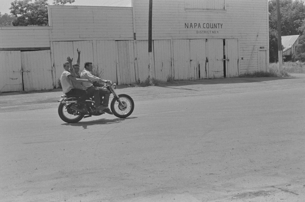 Young men ride a motorcycle through Monticello in 1956.
