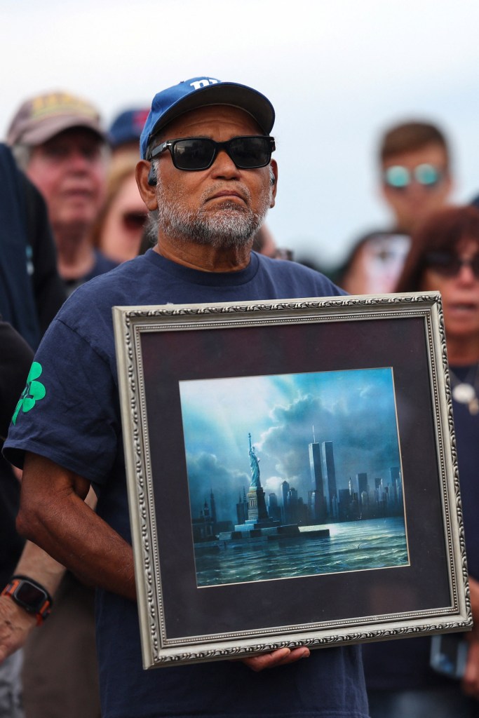 Man holding a framed illustration of the Statue of Liberty and the Twin Towers.