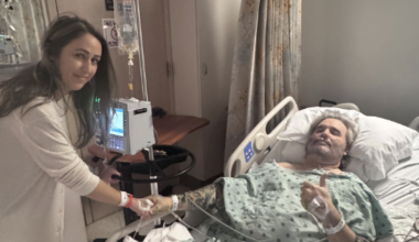 Woman visiting man in hospital bed.