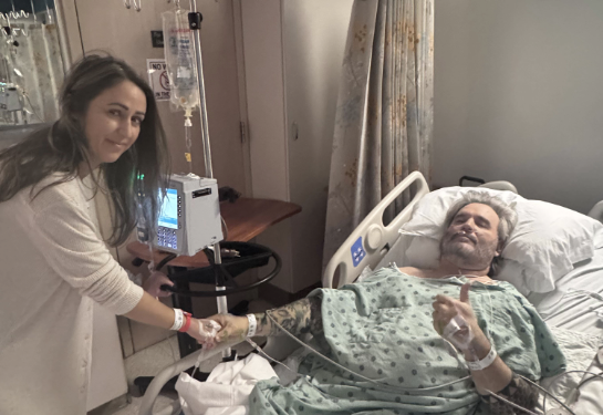 Woman visiting man in hospital bed.