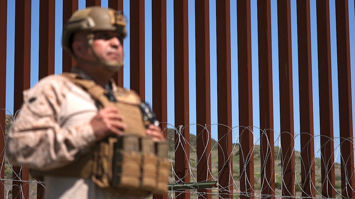 a border patrol agent stands in front of the trump border wall