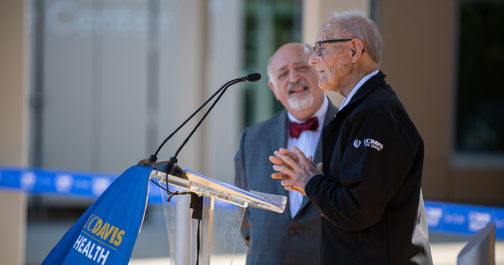 Ernest E. Tschannen stands behind a podium making remarks at an event