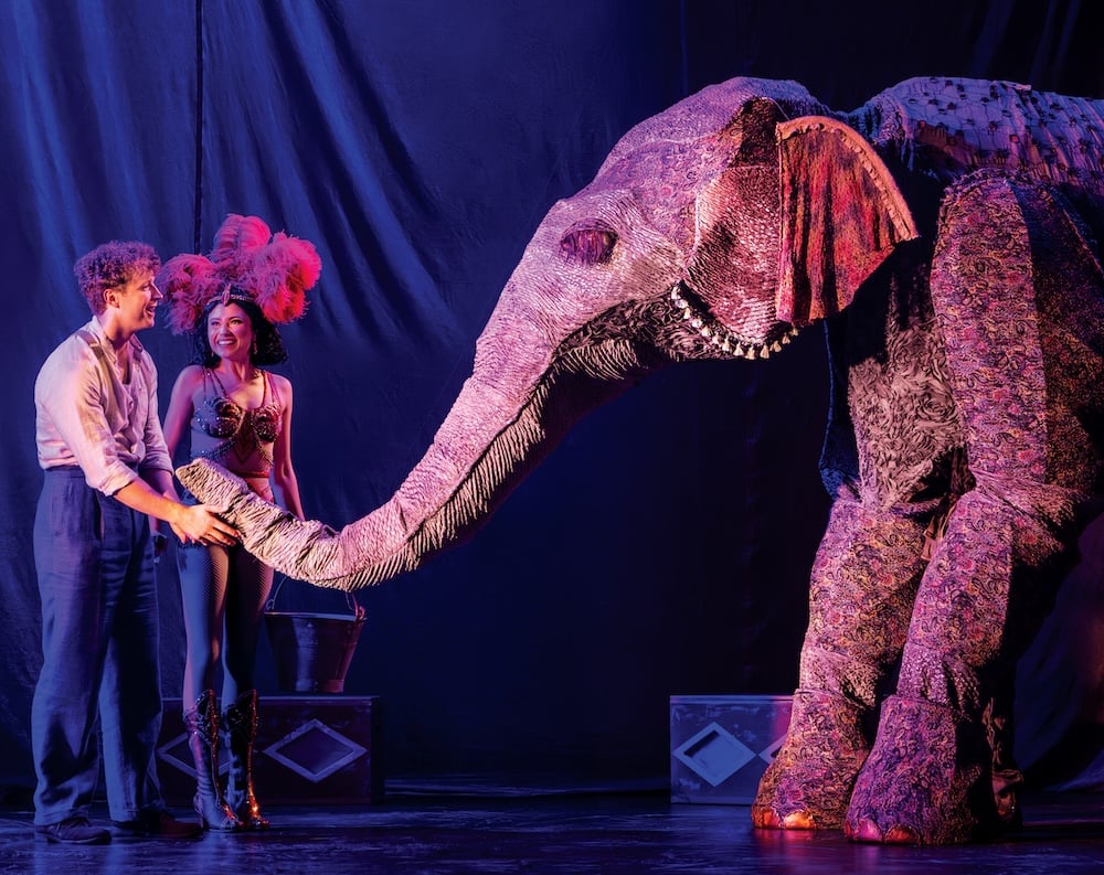 Two actors in Water For Elephants interact on stage with a large, meticulously created elephant puppet