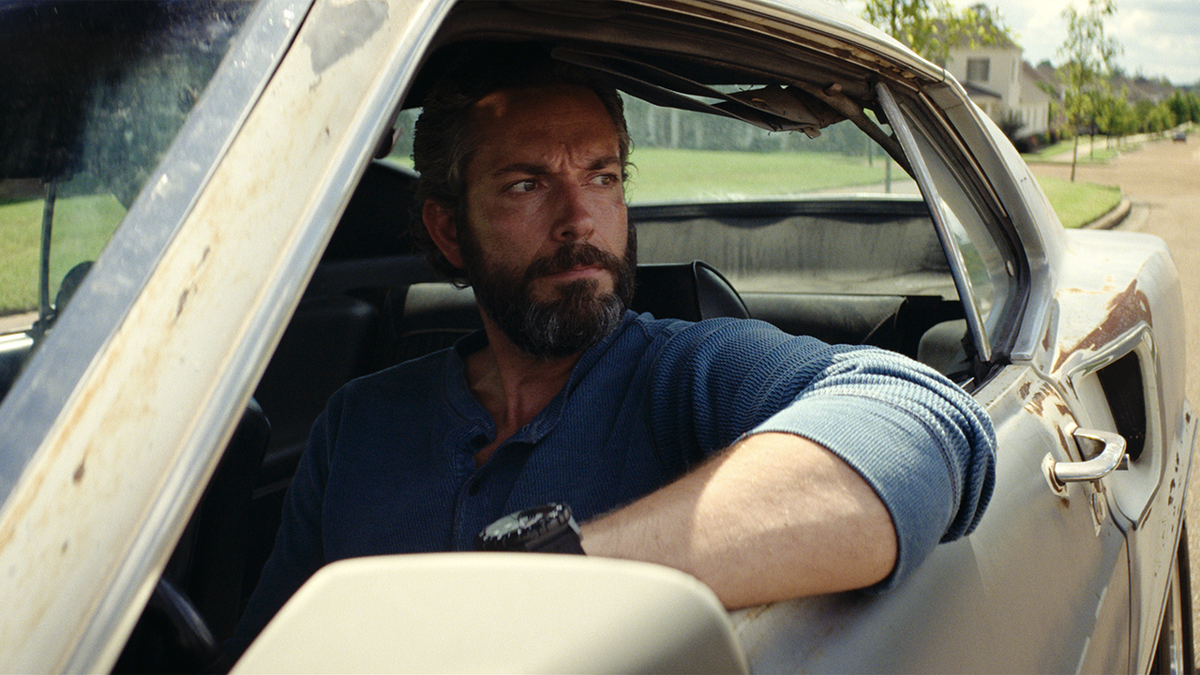 Zachary Levi looks out a car window in The Fix
