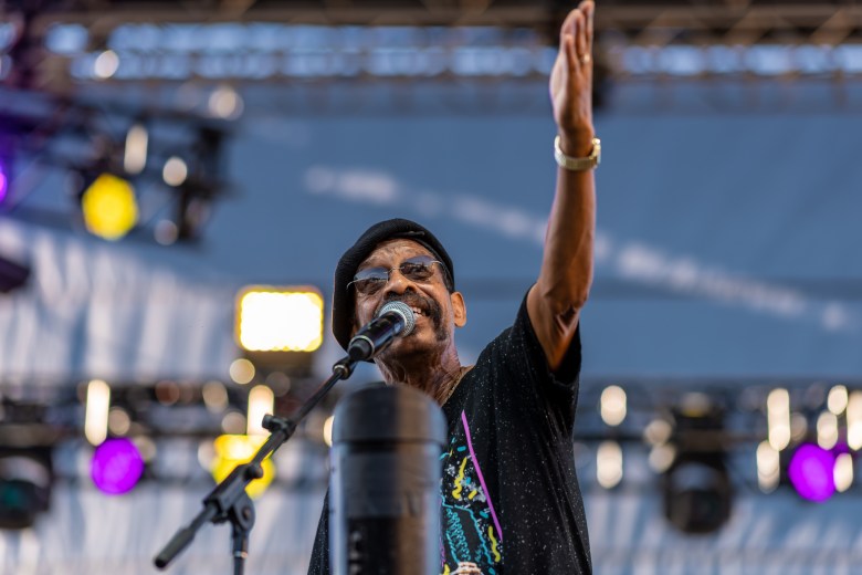 A man raising his arm while singing into a microphone.
