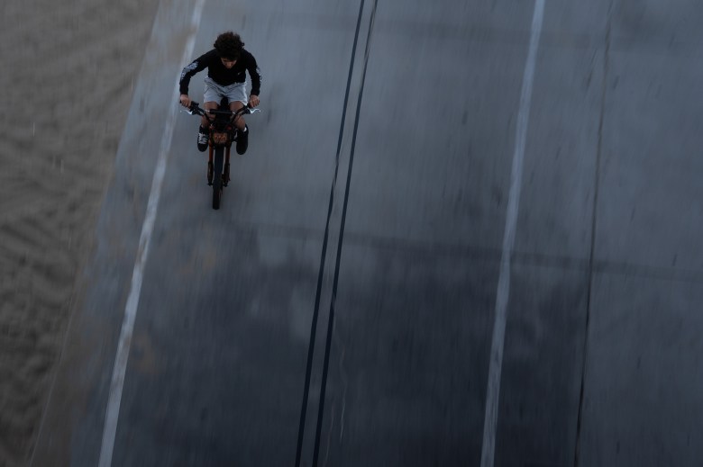 An aerial view of a person zooming through a pathway while riding tan electric bike.