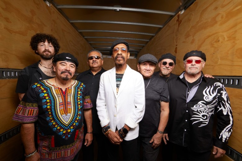 Seven older men stand and pose together. Five of them wear berets.