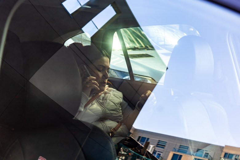 A San Francisco educator sits in the backseat of a car and talks on a smartphone.