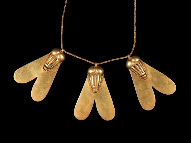 Gold necklace featuring three bee or insect-shaped pendants with heart-like wings, strung on a fine chain, against a black background.