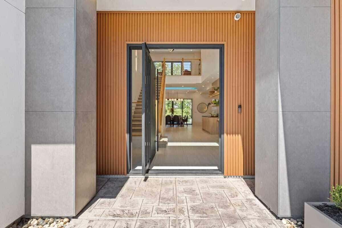 The glass-paneled pivot door opens into an entry foyer with ceilings rising 23 feet.