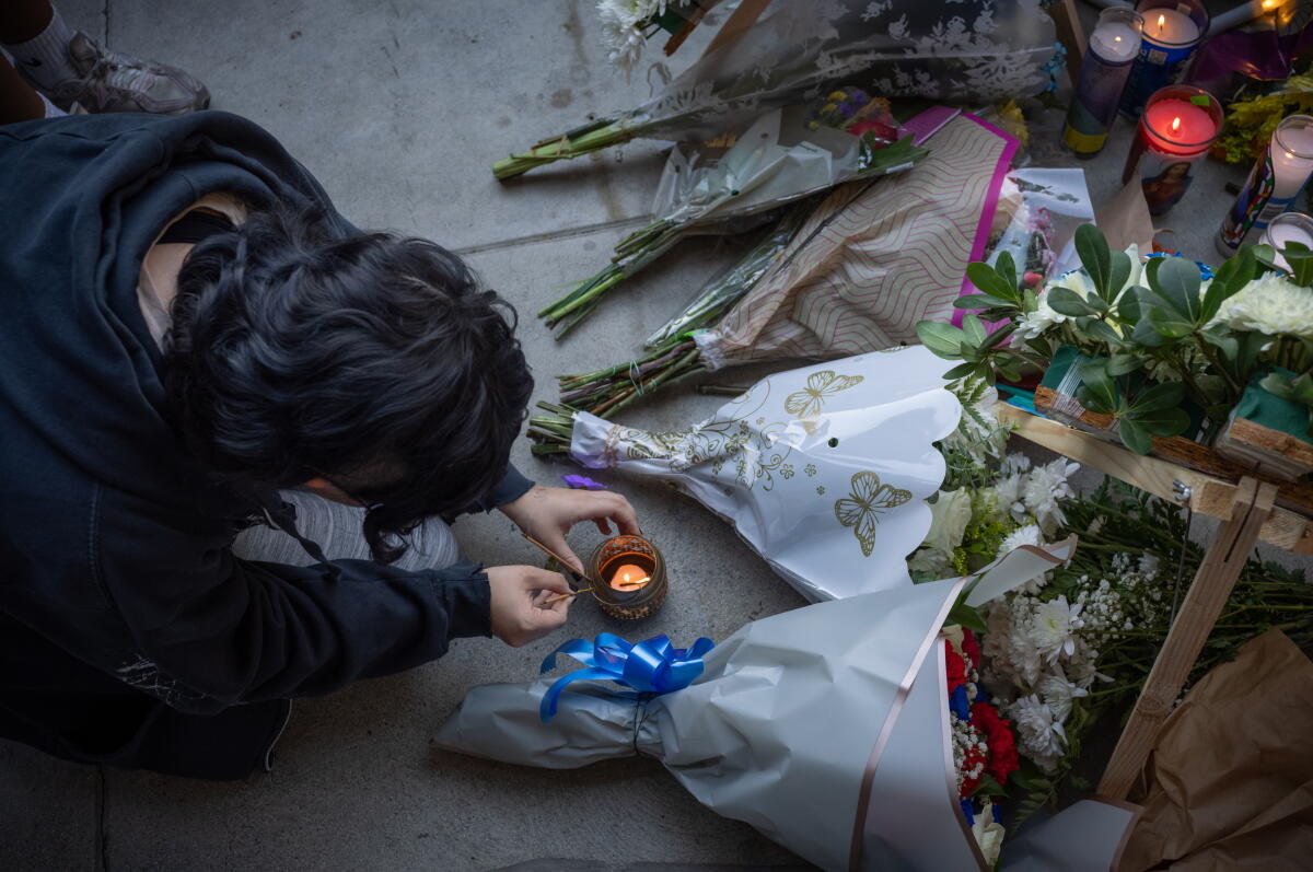 A student lights a candle to lay at a vigil