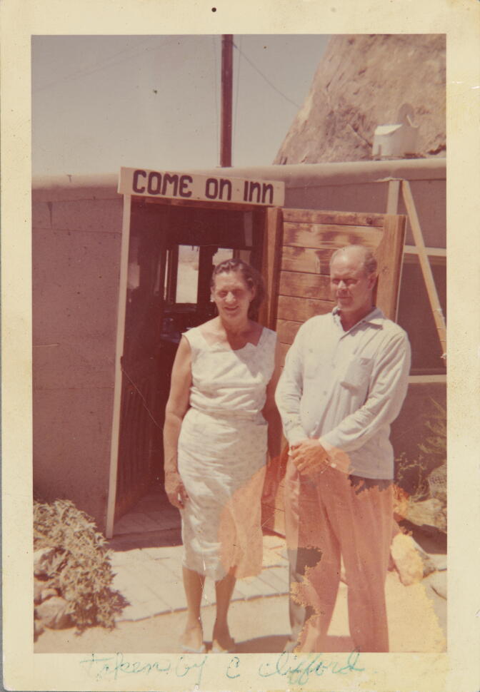 A man and woman stand outside a cafe with a sign that reads "Come On Inn."