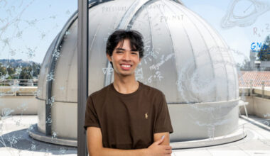 Julian Shapiro poses in front of a window overlooking an observatory
