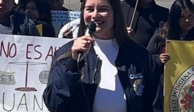 Hazel Davalos speaks in front of a crowd of demonstrators with handwritten Spanish posters calling for fair wages