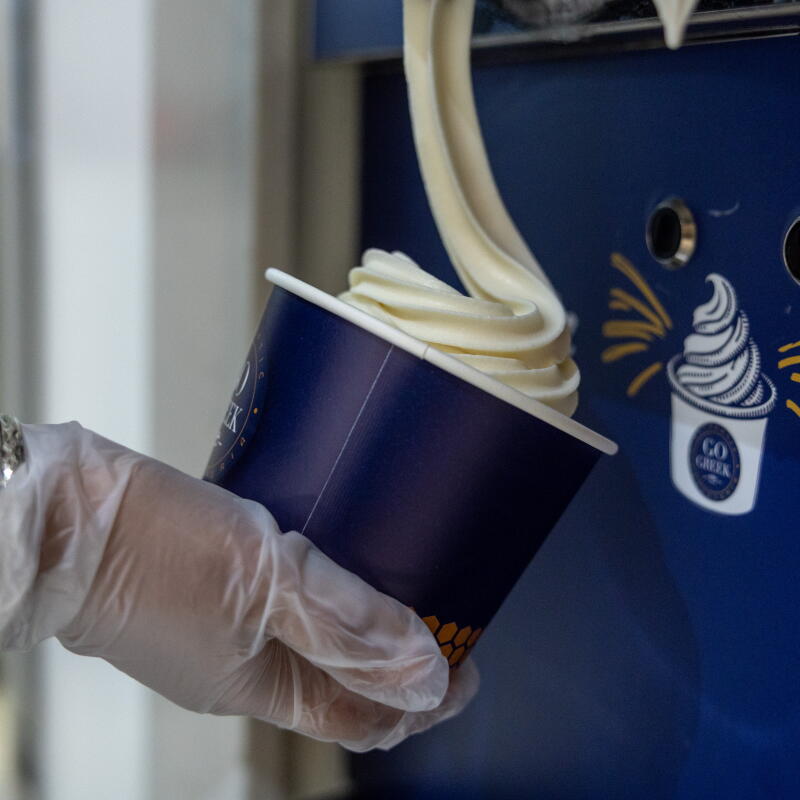 A Go Greek Yogurt employee fills a bowl with yogurt.