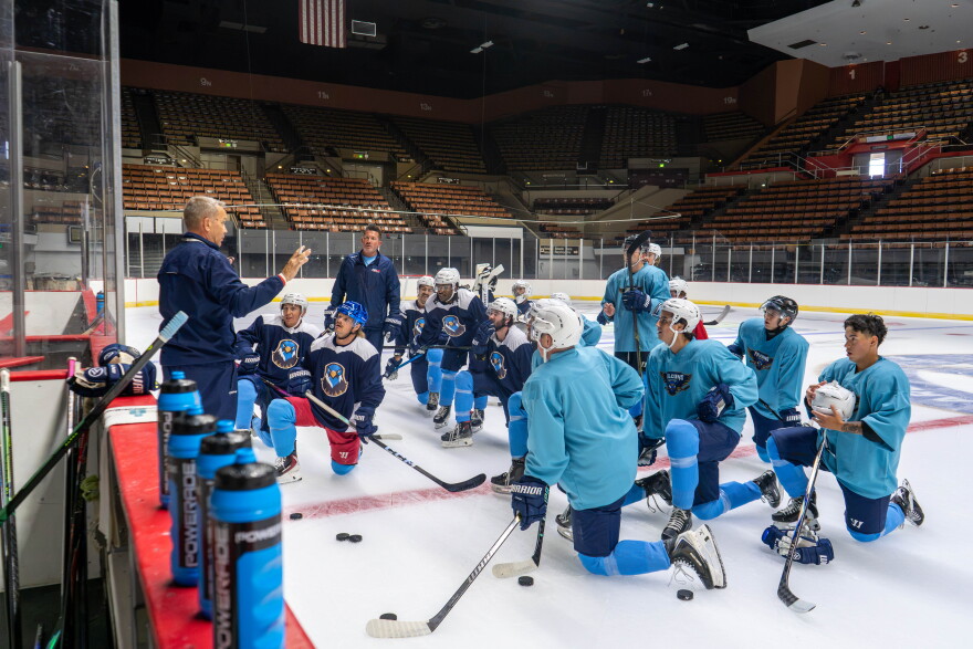The team kneels and head coach Iain Duncan goes over plays.