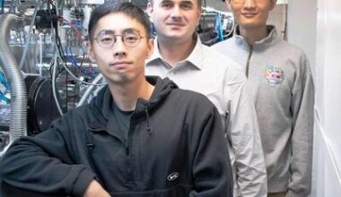 Three scientist standing in a lab next to equipment.