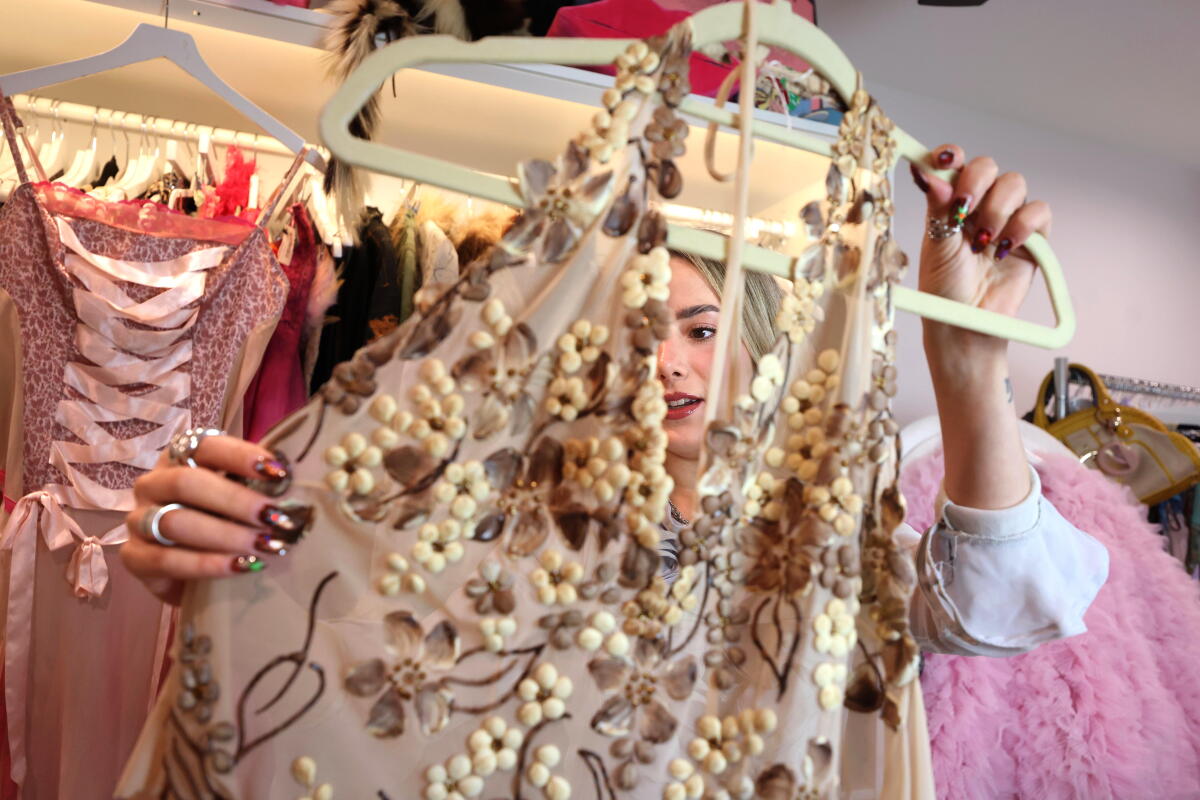 A woman holds up a dress.
