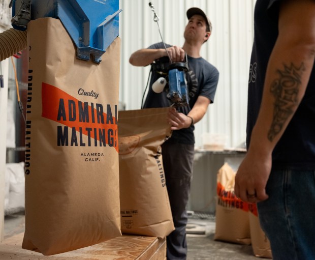 Derek Timm-Brock uses a machine to close the last ever batch of floor malt bags during the last day of operation of Admiral Maltings in Alameda, Calif. on October 2nd, 2026. (Douglas Despres for Bay Area News Group)
