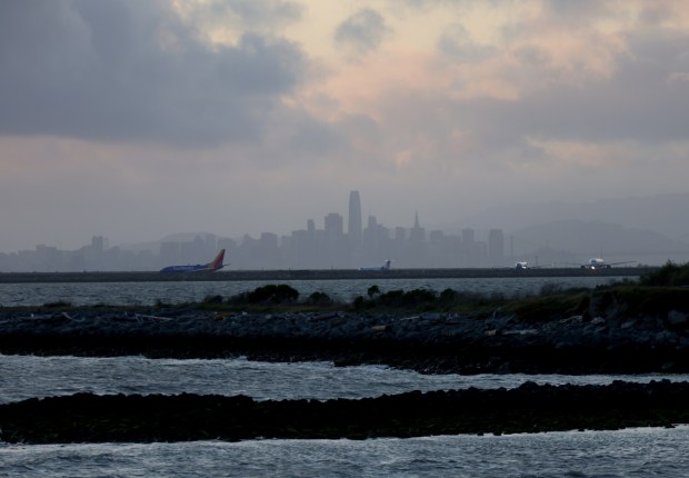 Planes taxi at Oakland International Airport as the last of the storm clouds hover over the San Francisco skyline as seen from Marina Park in San Leandro, Calif., on Tuesday, April 1, 2025. (Jane Tyska/Bay Area News Group)