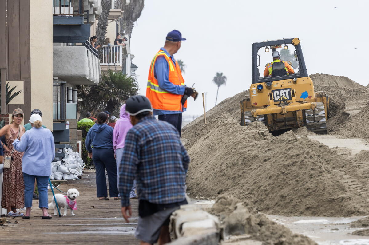 People gather along the boardwalk as heavy machinery builds sand berms on the Long Beach Peninsula on Saturday.