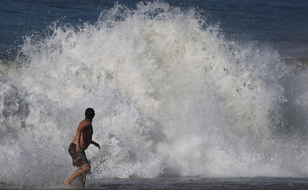 A man looks back as a large wave crashes on the shoreline in Laguna Beach 