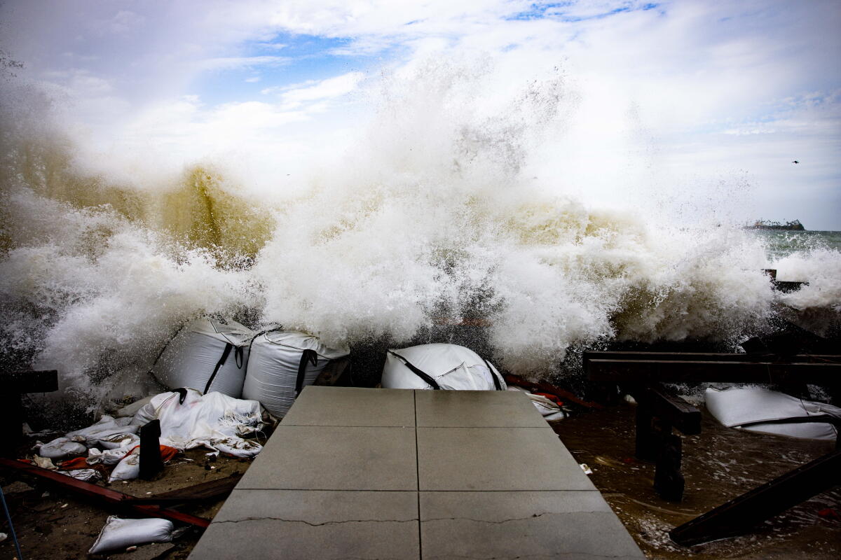 Waves crash against East Seaside Walk at Peninsula in Long Beach on Sunday.