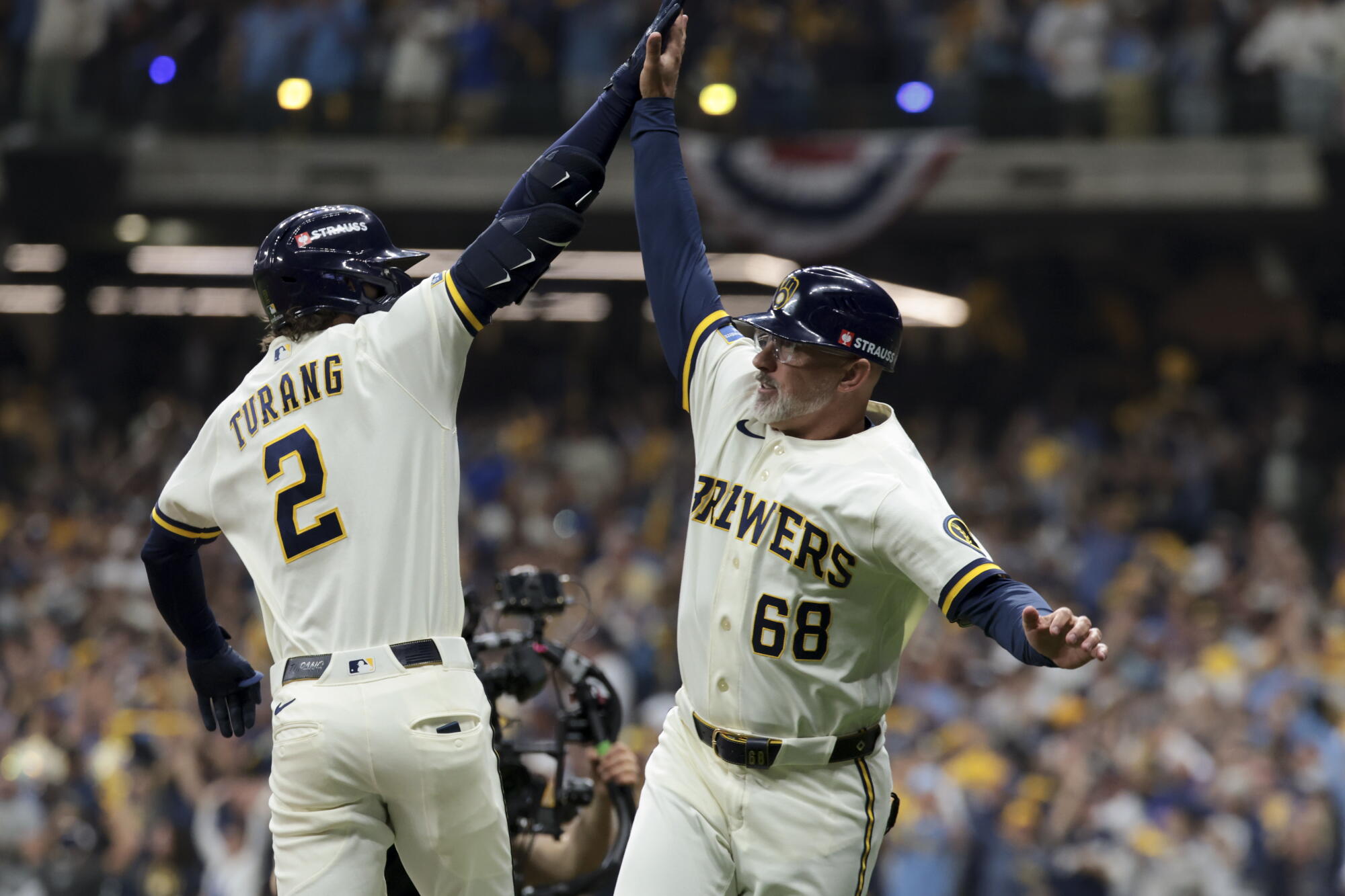 Milwaukee's Brice Turang celebrates with third base coach Matt Erickson.