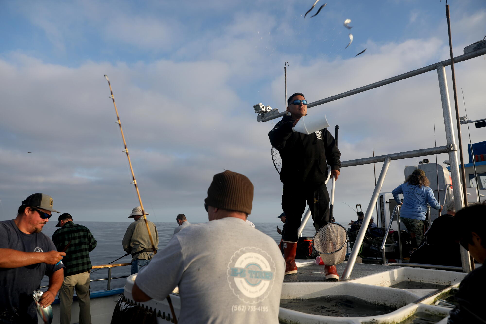 Eric Munoz, right, a deckhand aboard the Dana Pride, tosses anchovies in the ocean.