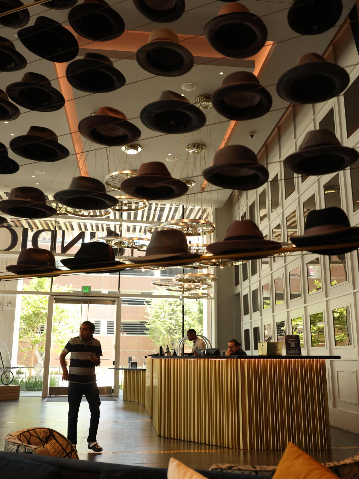 A visitor walks under a display of hats in a hotel lobby.