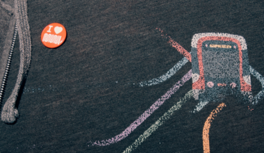 A dark hoodie features a red button reading "I ♥ MUJI" and a colorful stylized subway train graphic with lines representing tracks.