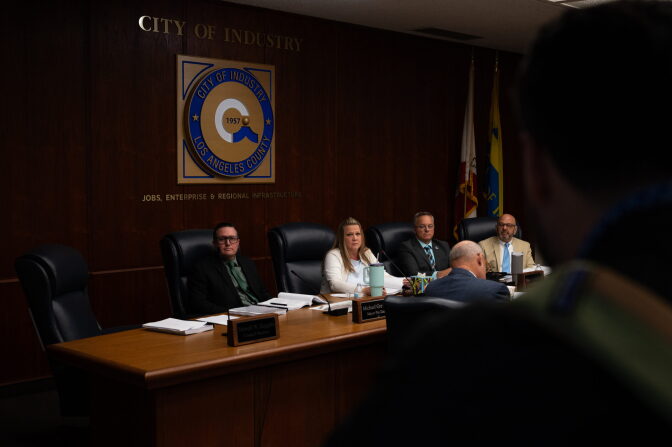 A person, out of focus in the foreground, faces a group of people sitting a table.